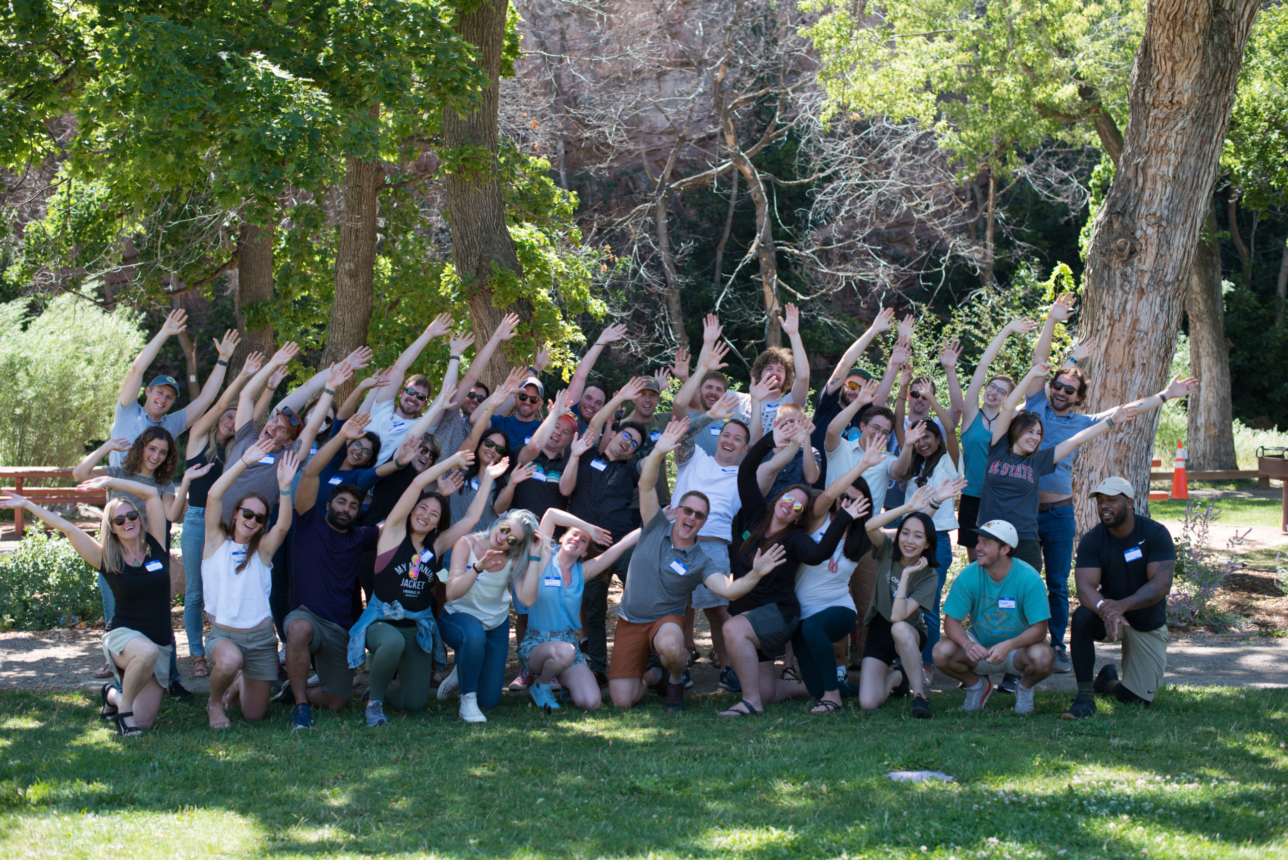 The Optera team gathers in a park on a sunny day, posing to the camera with their arms up as if on a roller coaster